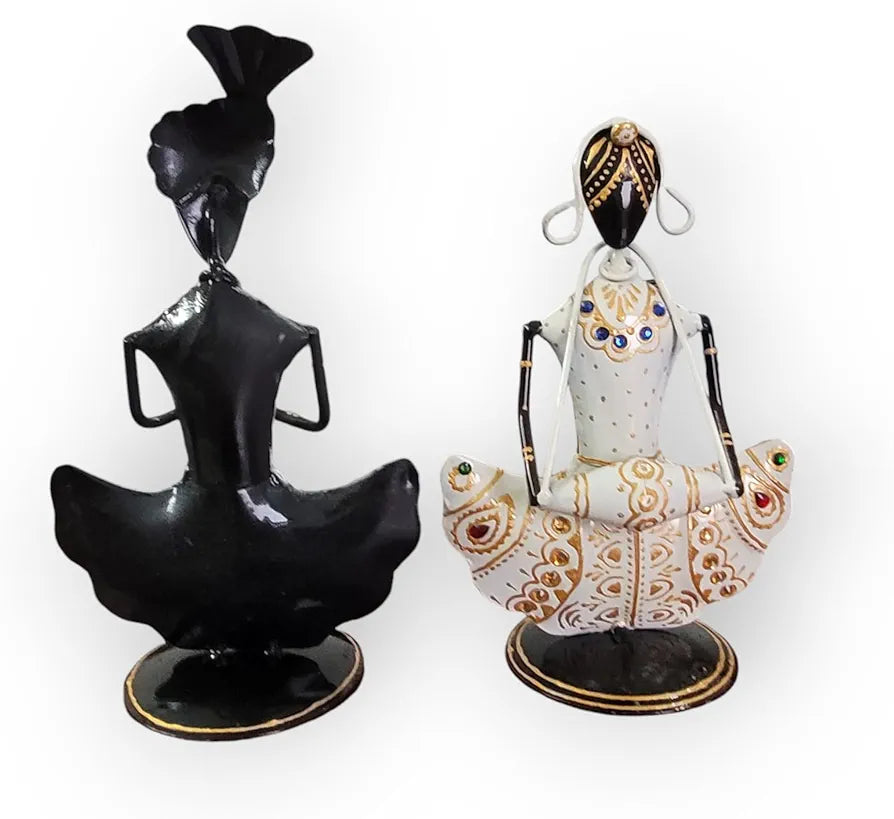 Two decorative figurines, one black and one with intricate white and gold patterns, on a white background.