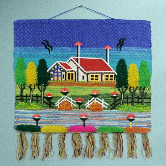 Decorative handwoven jute village scenery tapestry with a blue sky background styled as wall art in a modern living room