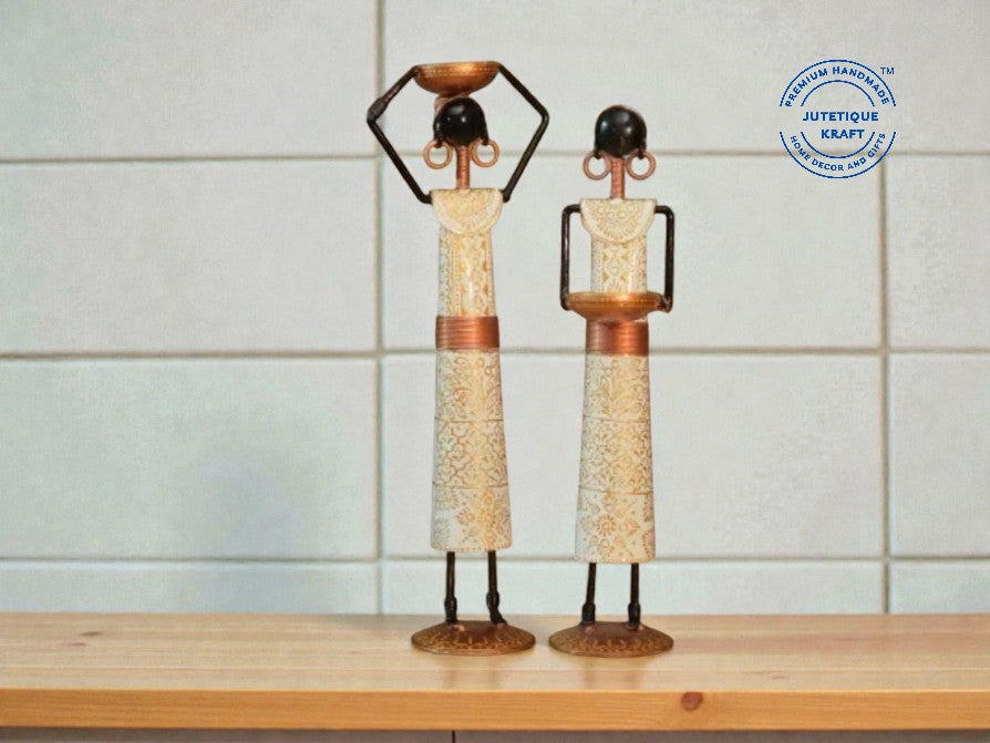 Elegant white handcrafted metal candle doll figurines displayed on a wooden surface