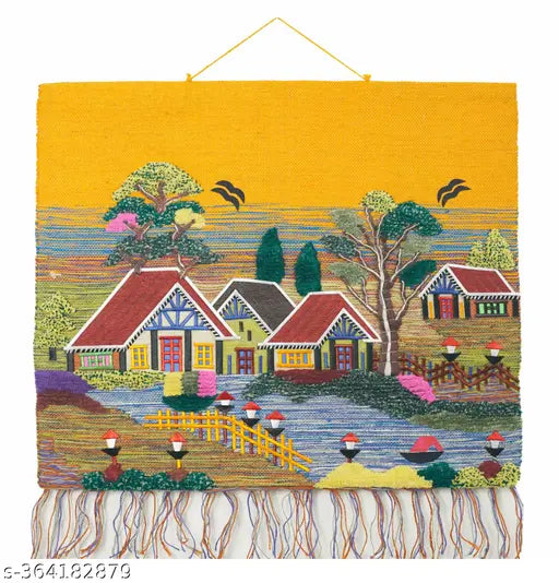 Embroidered wall art of a village scene with houses and trees on a yellow background.