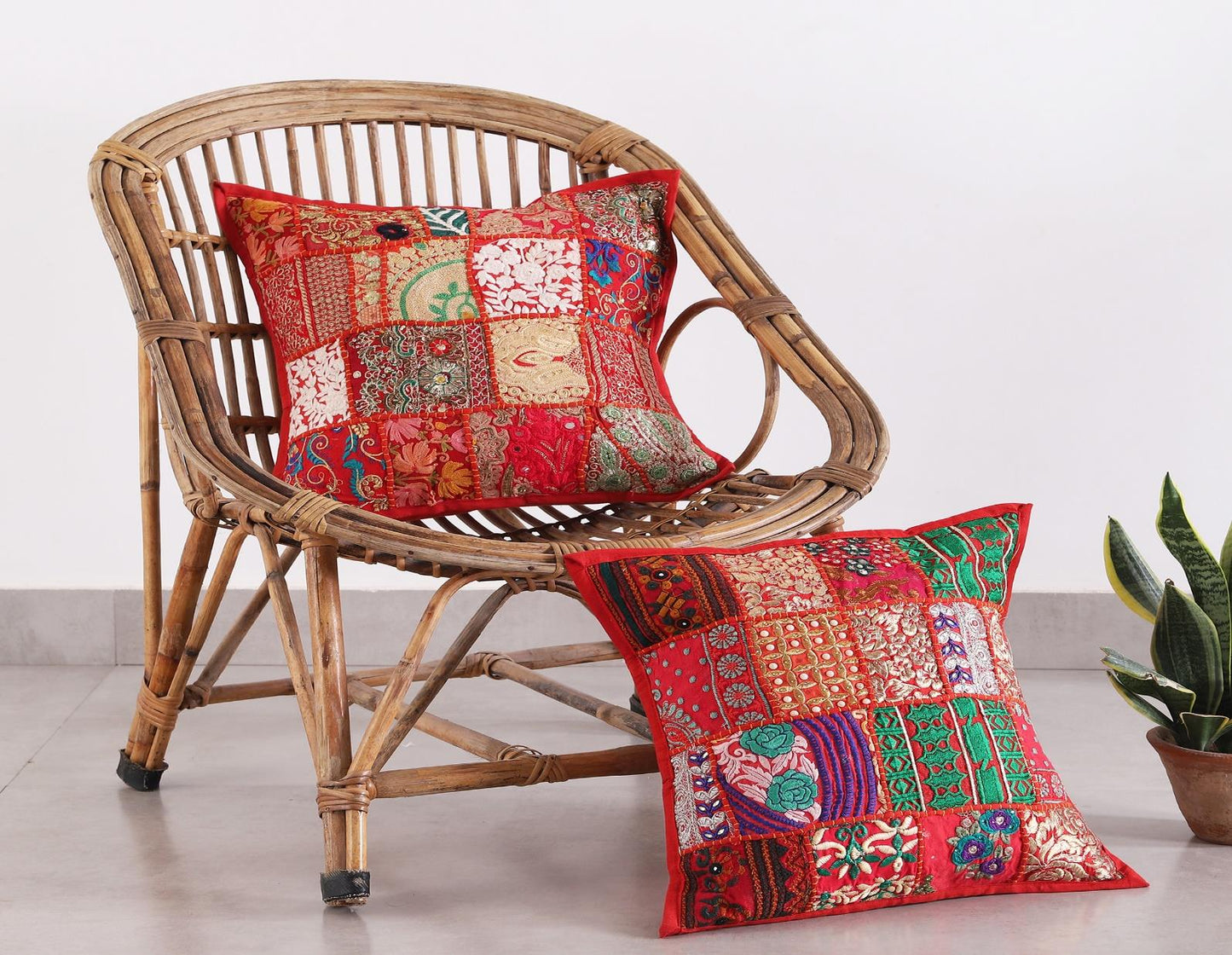 Handcrafted colorful patchwork cushion covers on a vintage wicker chair next to a white potted plant.