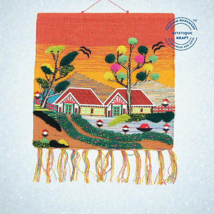 Detailed close up of a 30x30 GI Tagged Ghazipur jute wall hanging featuring rural village cottages and a river under a warm sunset sky horizon.
