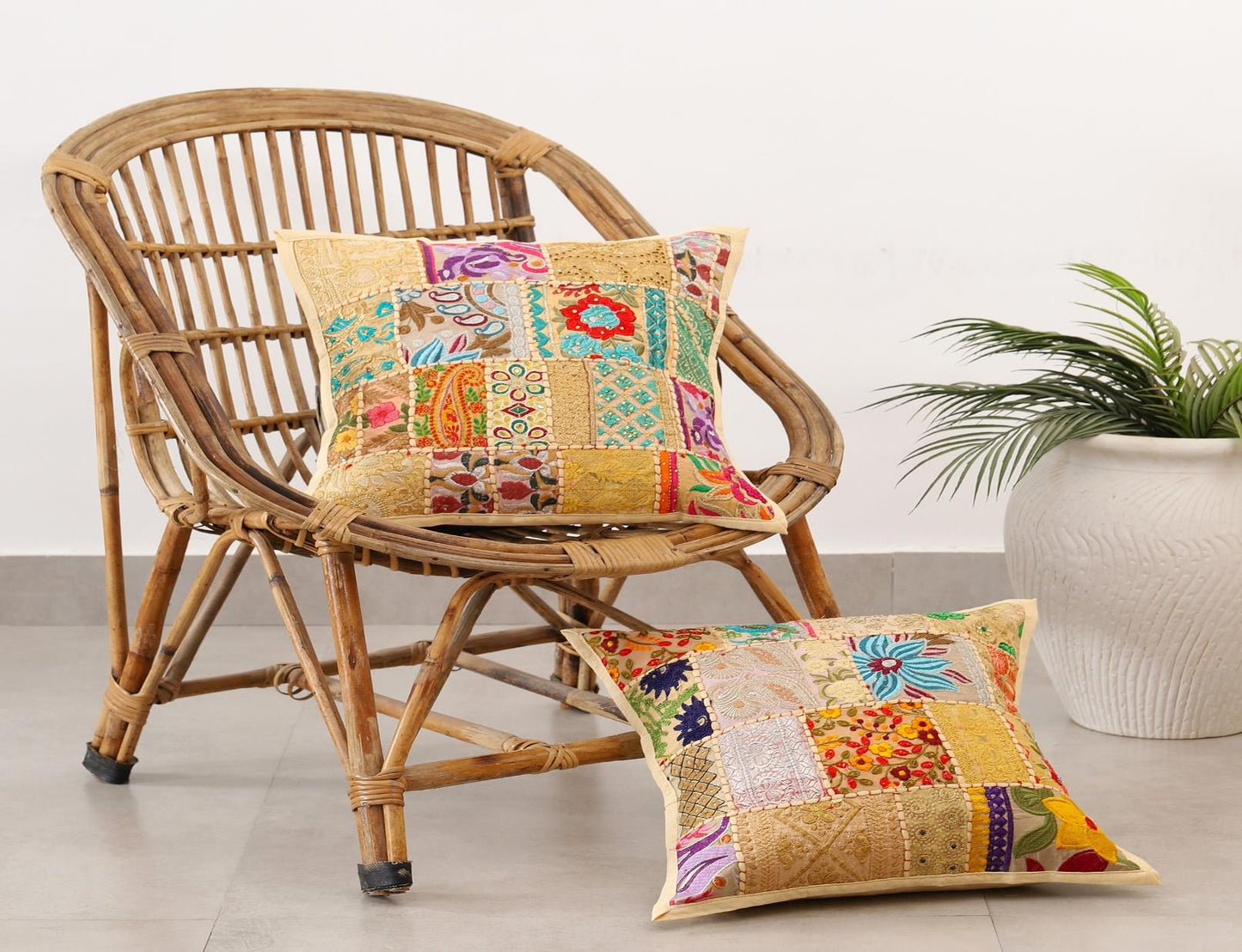 Wicker chair with colorful patchwork cushions and a plant in the background