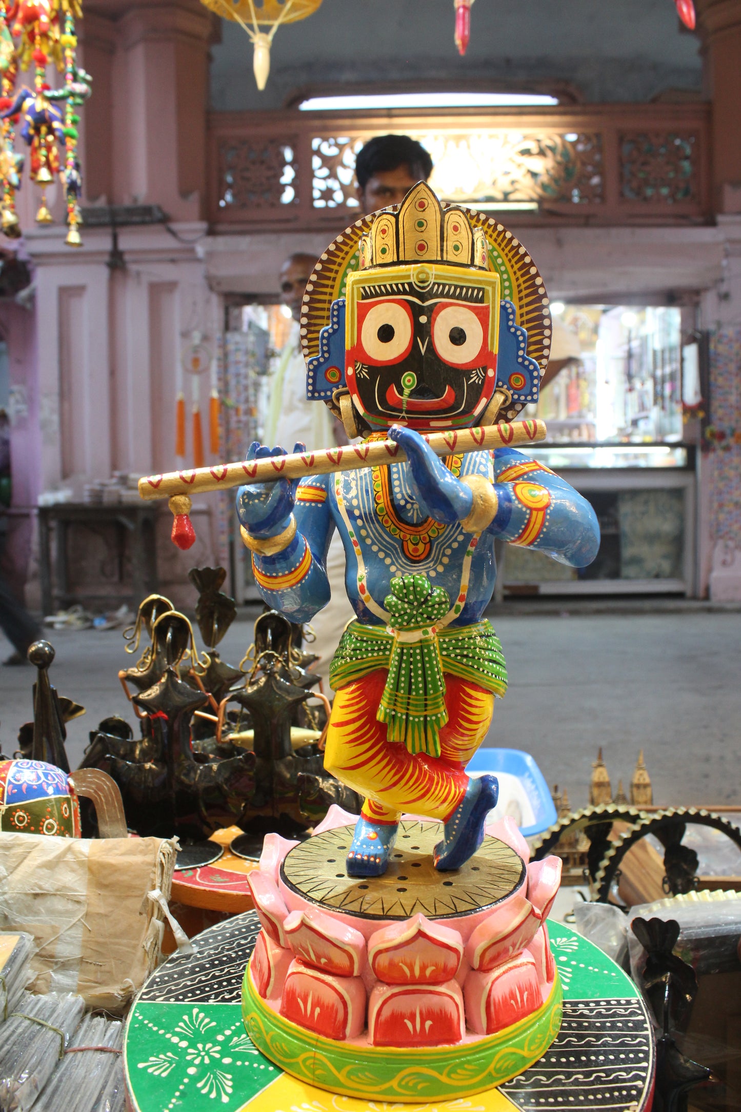 Intricate hand-painted facial features showcasing the distinct eyes of Lord Jagannath on a wooden flute-playing Krishna statue.