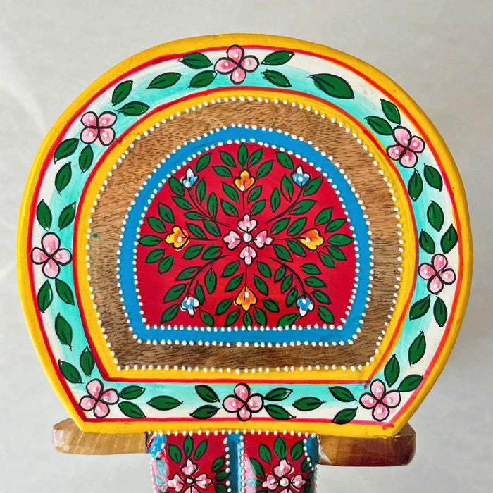 Top view of handpainted natural wood elephant stool showcasing traditional colorful floral patterns