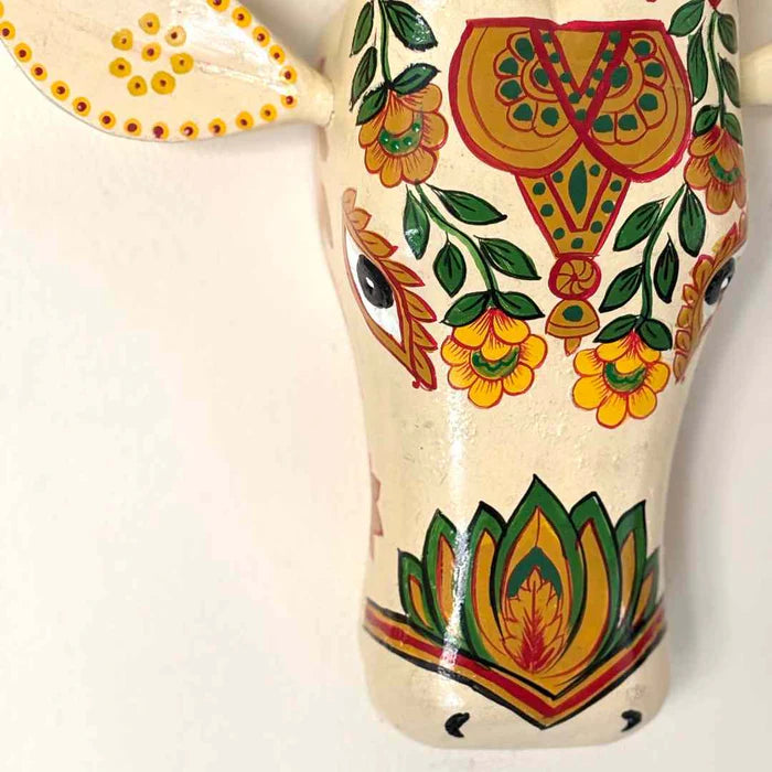 Hand-painted white wooden cow head wall decor featuring traditional Indian floral patterns and colorful horns.