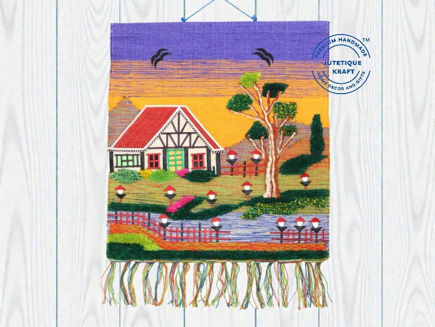 30 inch square GI Tagged jute wall hanging showcasing a rural village cottage scene with a blue sky background