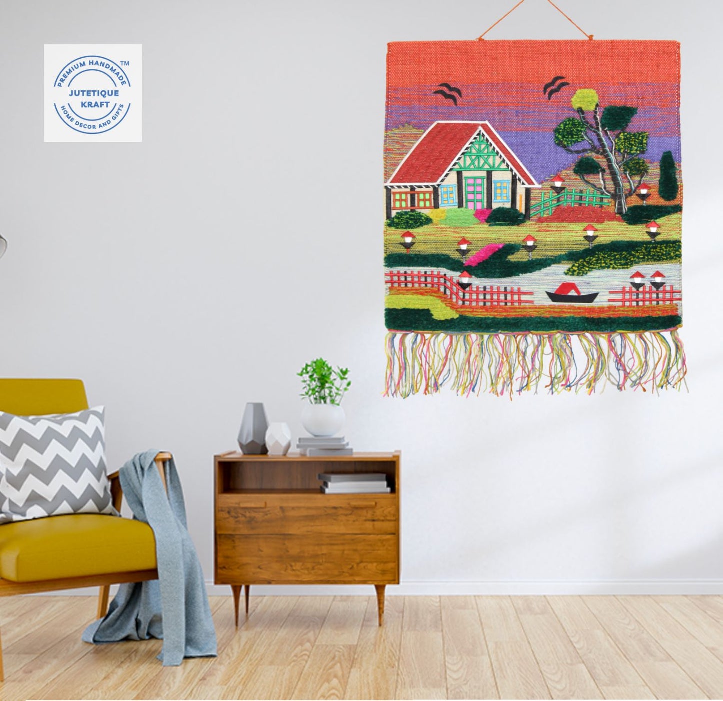 Earthy natural fiber wall art depicting an Indian countryside cottage under an orange sunset horizon