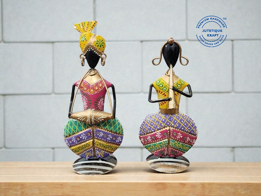 Handcrafted purple and pink metal musician couple statues displayed on a rustic wooden tabletop