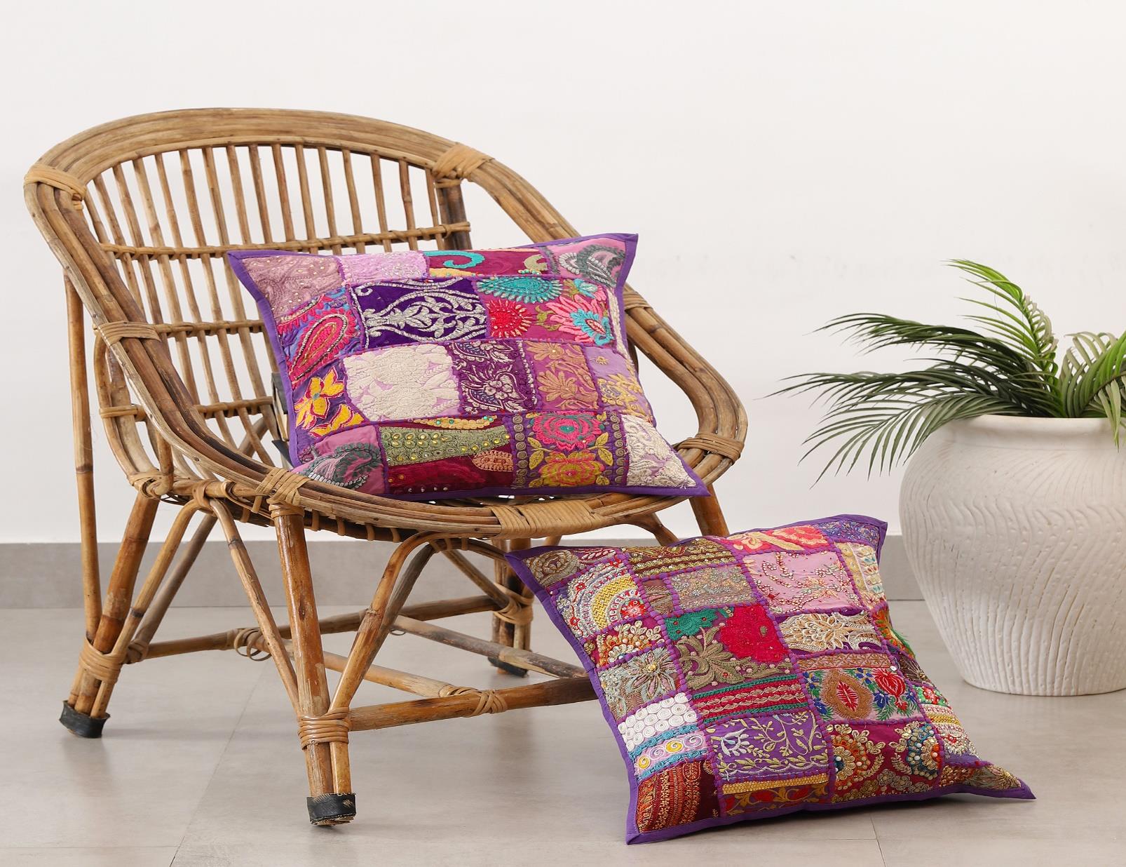 Bohemian style Khambadiya patchwork cushion covers from The Sia Collection displayed on a rattan chair.