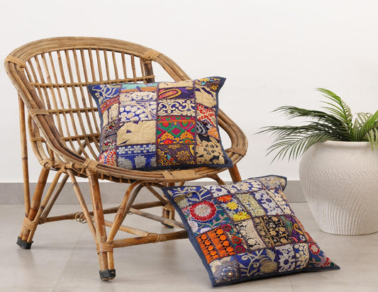 Handcrafted colorful patchwork cushion covers on a vintage wicker chair next to a white potted plant.