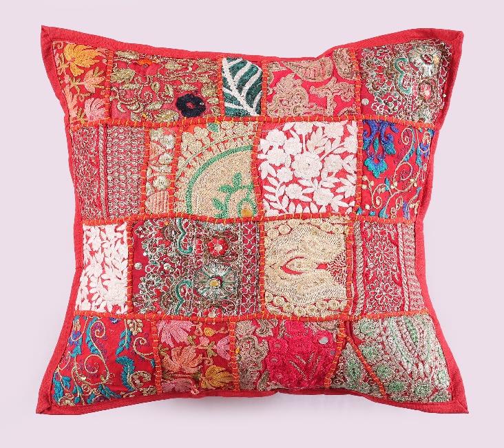 Handcrafted colorful patchwork cushion covers on a vintage wicker chair next to a white potted plant.