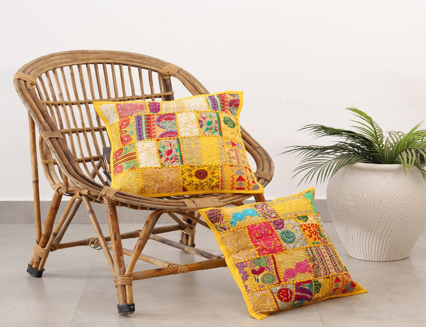 Bohemian style Khambadiya patchwork cushion covers from The Sia Collection displayed on a rattan chair.