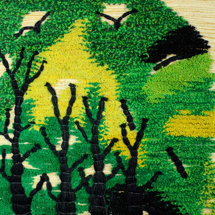 Close up of the rich textured artwork showing green and black wool weaving details on the nature tapestry