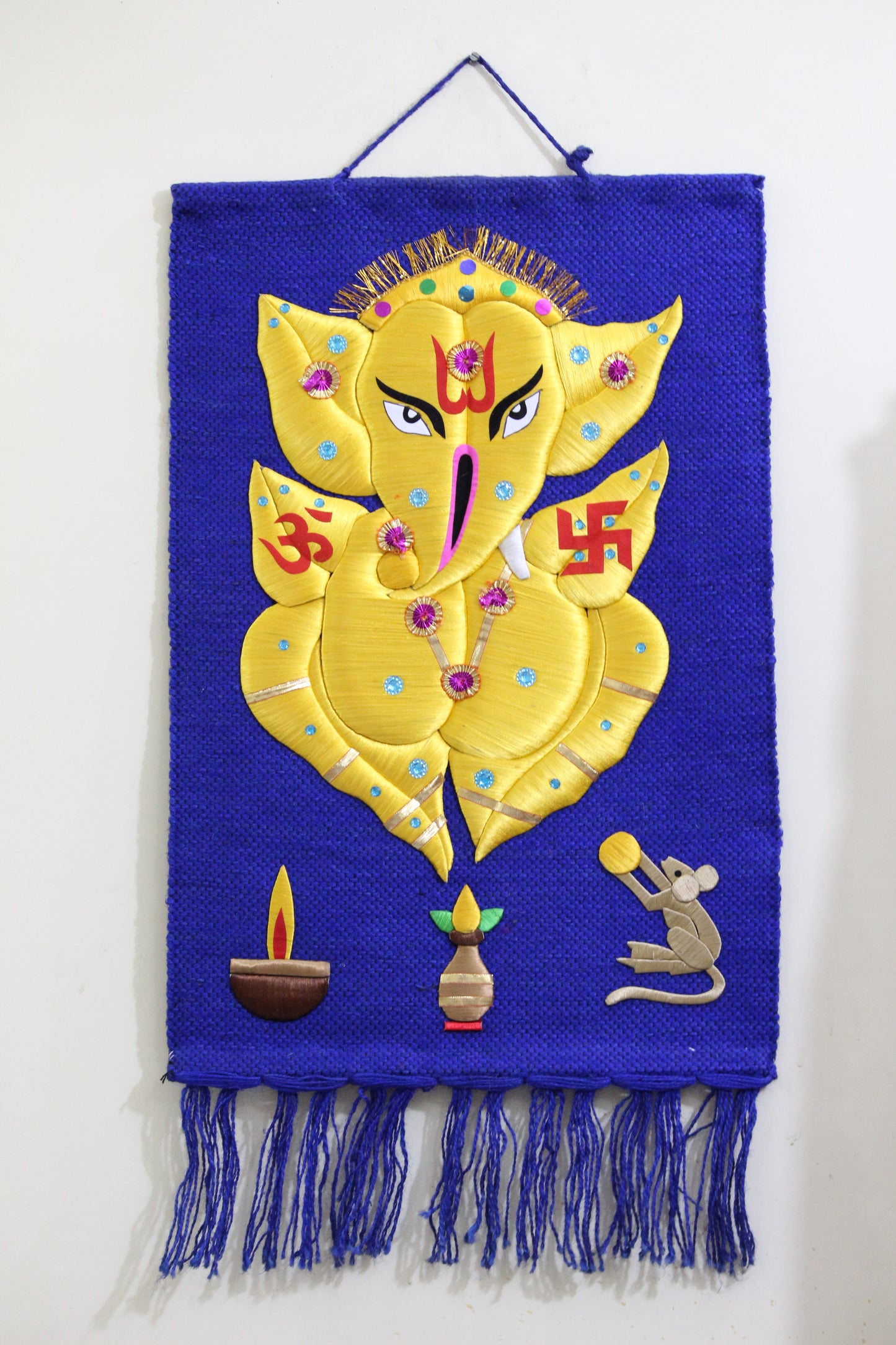 Decorative yellow and blue silk thread Lord Ganesha design with hanging fringes on woven jute fabric