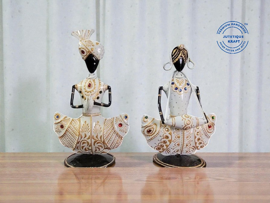 Two decorative statues on a wooden surface with a white curtain background.