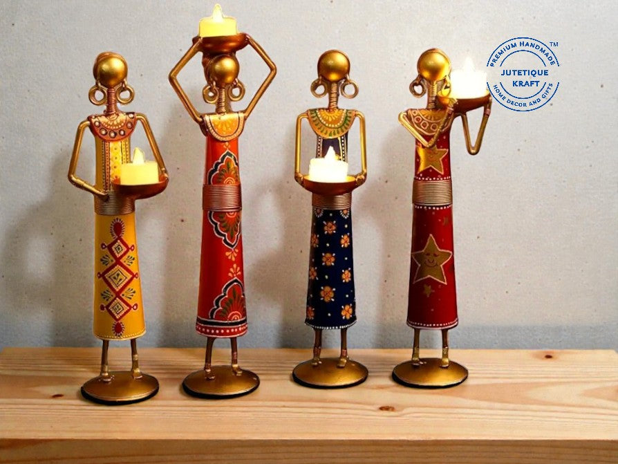 Four decorative candle holders shaped like people on a wooden surface with a plain background.